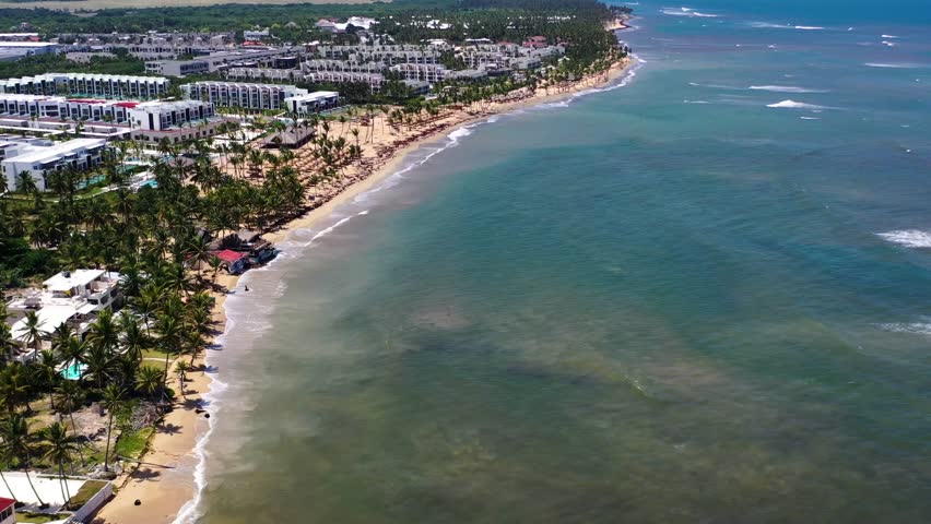 Aerial view of waves crashing on the stunning beach in Punta Cana, Dominican Republic, showcasing the vibrant blue waters and picturesque coastline.