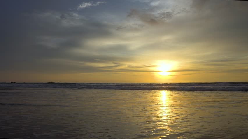 Unidentified surfers silohuettes on Beach with a dramatic sunset