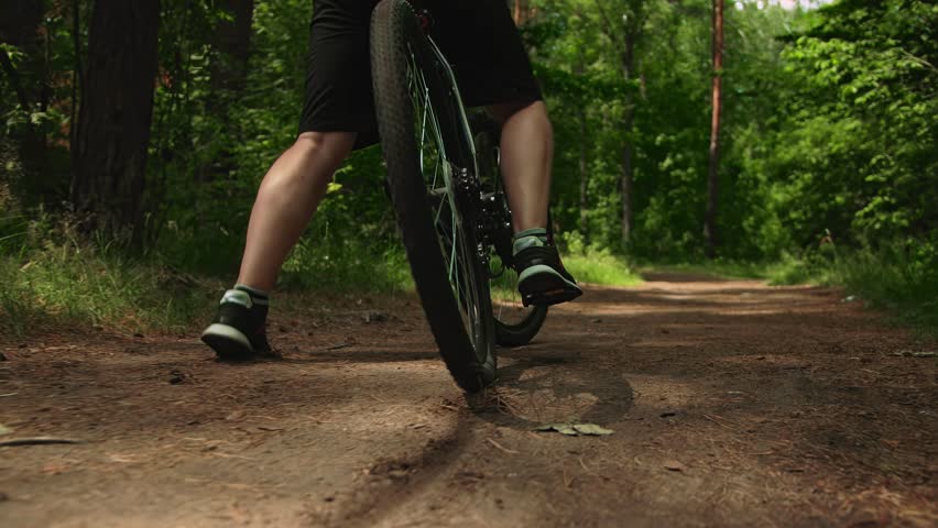 Guy gets on his bike starts riding through forest and slows down abruptly, cyclist brakes stops. Off-road trail riding. Weight loss training, adult man with hardtail mountain bike