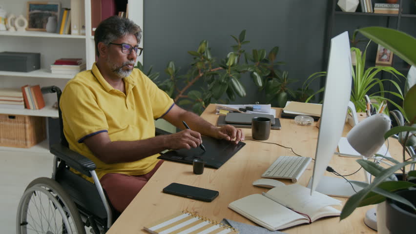 Graphic designer in wheelchair drinking coffee and drawing on tablet