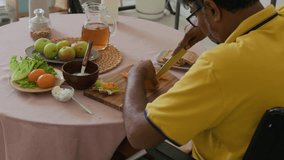 Mature wheelchaired man cutting tomatoes for sandwich at kitchen - Powered by Shutterstock - Get 15% off with code: PIKWIZARD15