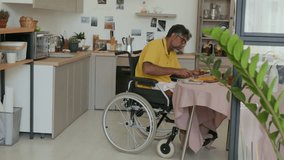 Man in wheelchair eating sandwiches for breakfast at home - Powered by Shutterstock - Get 15% off with code: PIKWIZARD15