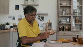 Cheerful man in wheelchair cooking sandwich at home kitchen - Powered by Shutterstock - Get 15% off with code: PIKWIZARD15