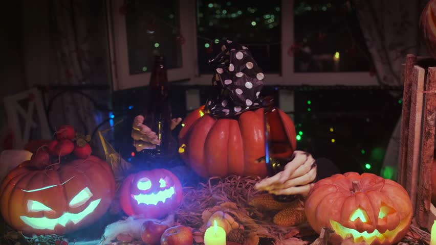 Spooky fun halloween decoration with rotating pumpkin head dancing with two beer bottles against festive lights.