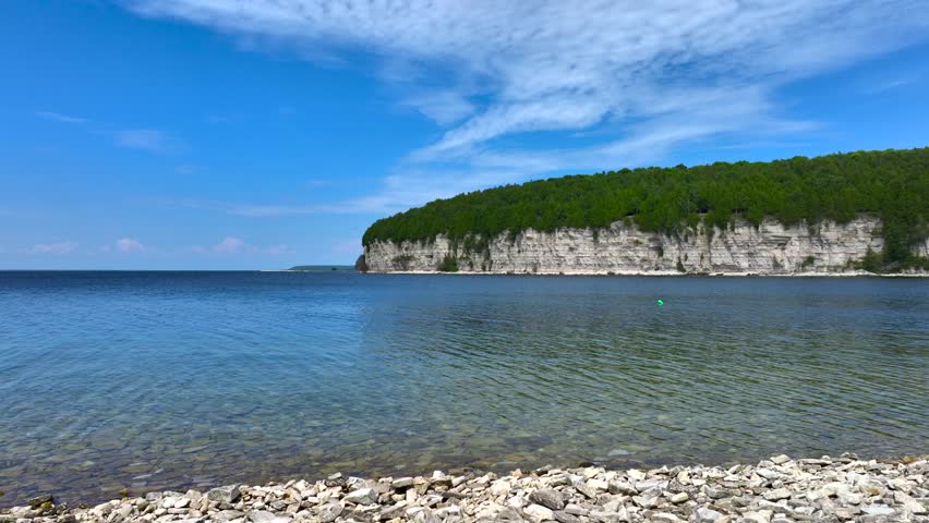 Aerial drone footage of Fayette Park and striking limestone cliffs in Fayette, Michigan on a beautiful and warm Summer day in July. Blue sky and wind turbines above calm Lake Michigan
