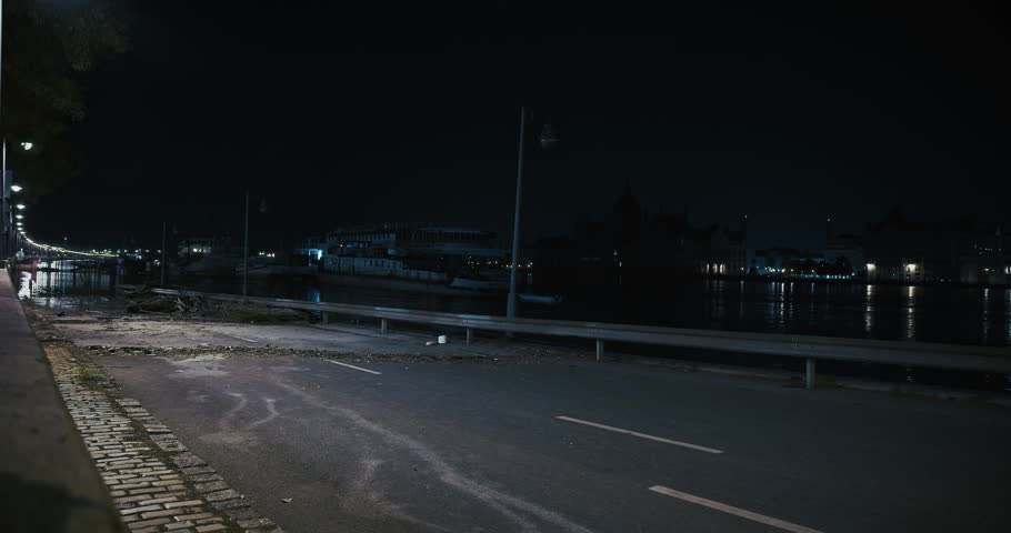 Flood debris scattered across a deserted road at night by the river in Budapest, Hungary