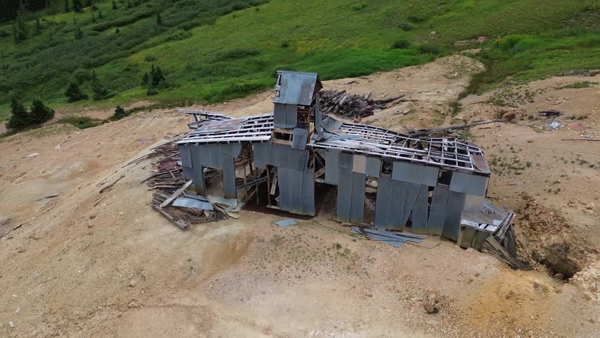 Aerial flyover shot of an abandoned, very decayed mine in the San Juan Mountains near Silverton Colorado. Rotating shot that circles the structure.