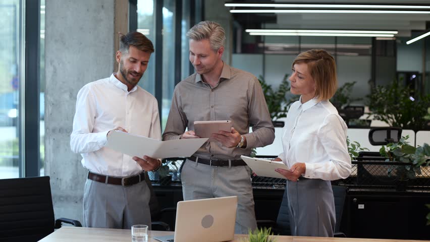 Three business people discussing work together using a tablet and laptop taking notes in a modern office - Powered by Shutterstock - Get 15% off with code: PIKWIZARD15