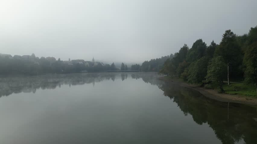 morning mist on the lake. Dron flies over the lake. Trees are reflected in the lake and fog rises above the surface of the water. Fuzine, Croatia