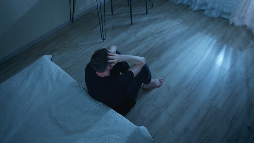 Lonely man sitting on the floor in the room in a state of depression. Concept of mental health, problems and stress. Psychological disorder.