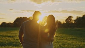 A couple stands embraced in a lush green field, watching the sun set on a warm evening. The golden light casts a beautiful glow, creating a romantic atmosphere around them. - Powered by Shutterstock - Get 15% off with code: PIKWIZARD15