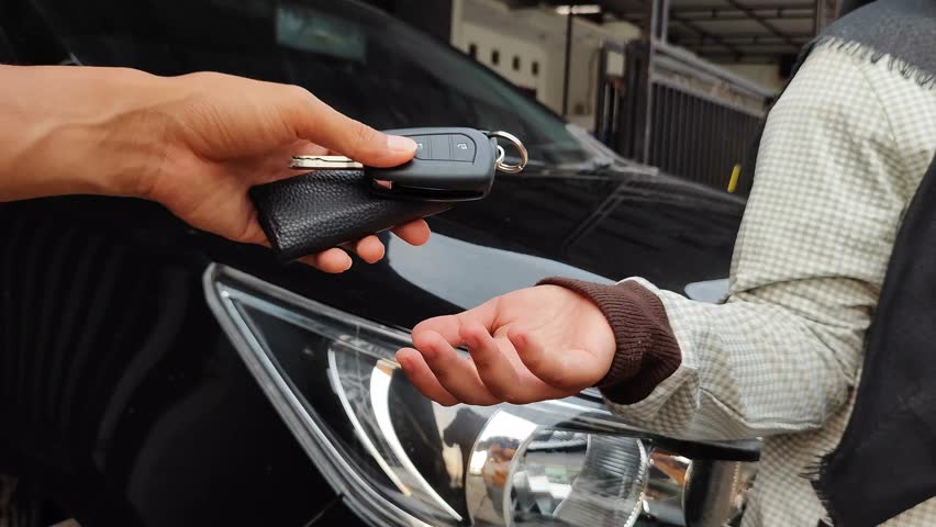 A rental agent's hand hands over the car keys to a customer. Car rental concept.