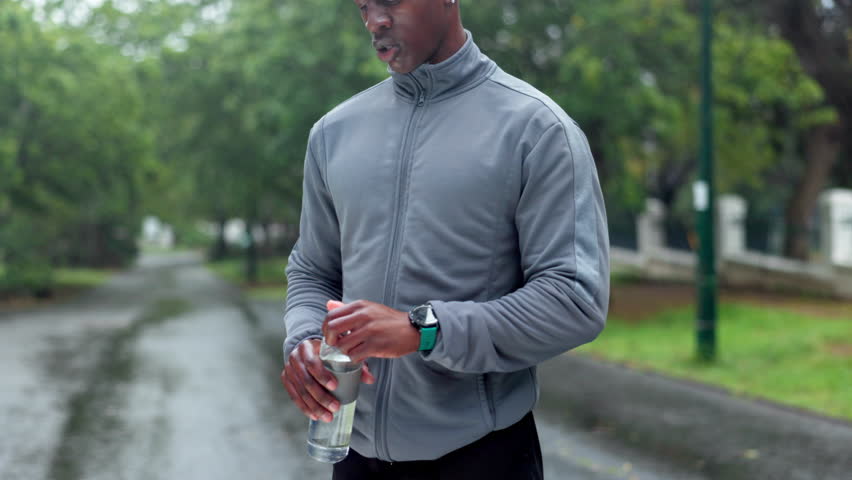 Workout, break and black man drinking water in nature for training, refreshment and fitness hydration. Athlete, tired and runner with bottle of h2o in park for sports recovery, exercise and nutrition