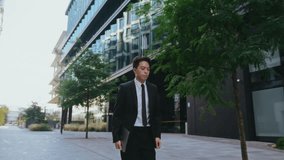 Young Asian businessman in formal suit walks glancing at watch on sidewalk. Man office employee carries laptop hurrying for work in downtown. Manager late for meeting - Powered by Shutterstock - Get 15% off with code: PIKWIZARD15