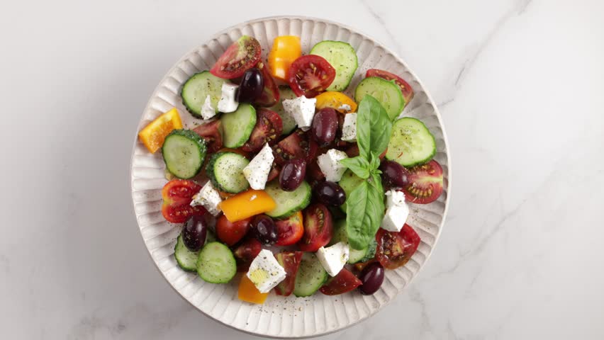 Greek salad on plate rotation top view on light surface food