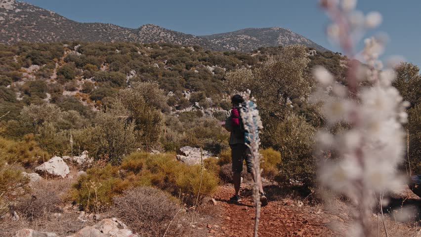 A happy male tourist with a large hiking backpack walks route along the seashore