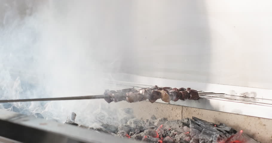Chef grilling liver kebab on barbecue charcoal grill. Traditional Turkish kebab grilled on skewers