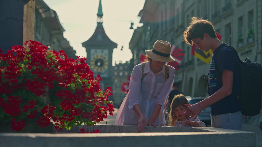 Bern old city, drinking fountain wit peoples, view of Zytglogge medieval tower. Switzerland