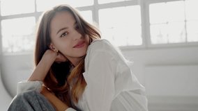 A tranquil setting capturing a young woman sitting casually on the floor in a minimalist room bathed in natural light. Young Woman Relaxing in Bright Room with Casual Attire - Powered by Shutterstock - Get 15% off with code: PIKWIZARD15