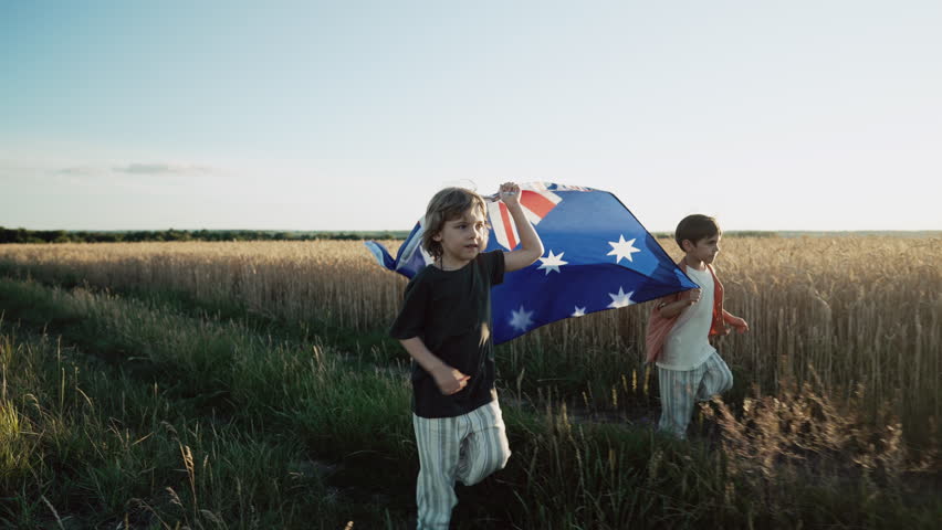 Australian little boys - sons patriots with national flag on sky background at sunset. Australia celebration banner, Anzac day, commonwealth