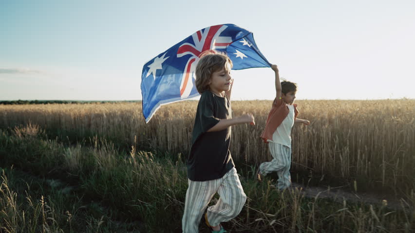 Australian little boys - sons patriots with national flag on sky background at sunset. Australia celebration banner, Anzac day, commonwealth