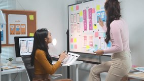 Two female web designers are collaborating on a project, brainstorming and making adjustments to the user interface - ui - design on a whiteboard - Powered by Shutterstock - Get 15% off with code: PIKWIZARD15