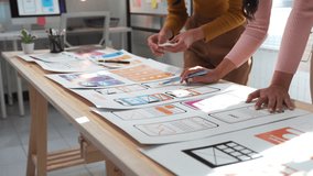 Two female ux designers collaborate on a mobile application prototype, discussing ideas and refining the wireframe at a table in a modern office environment - Powered by Shutterstock - Get 15% off with code: PIKWIZARD15