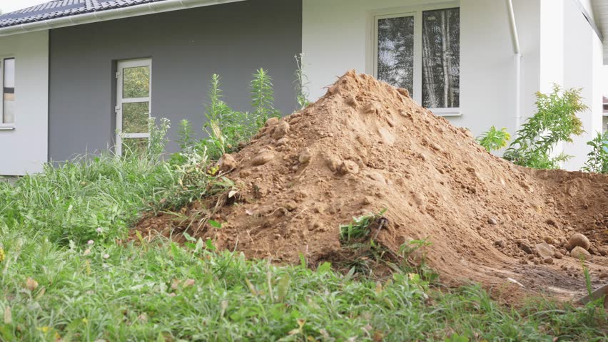 modern big yellow tractor works with sand on the construction site of a country house