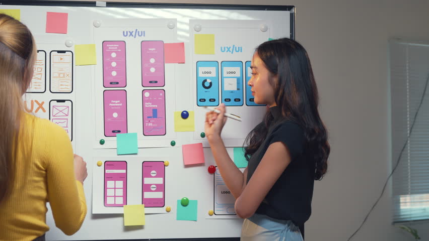 Two female web designers brainstorm and plan user experience design for a mobile application, focusing on user interface elements and collaboration strategies - Powered by Shutterstock - Get 15% off with code: PIKWIZARD15