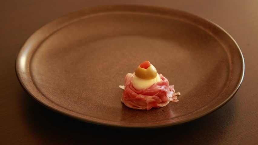 woman hands preparing  Spooky Halloween Eyeball Finger Food with Prosciutto, Mozzarella, and Green Olives