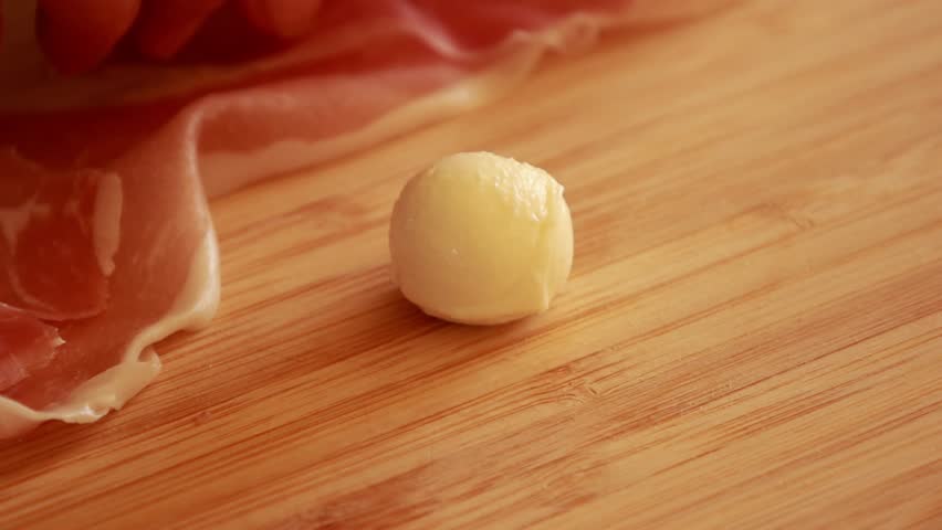 woman hands preparing  Spooky Halloween Eyeball Finger Food with Prosciutto, Mozzarella, and Green Olives