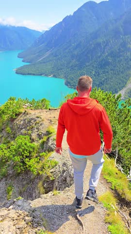 A hiker relishes the breathtaking and stunning views along the picturesque trail at Lake Plansee in Tyrol, Austria