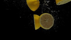 Slow motion yellow lemon halves falling into transparent water on black background. Fresh citrus splashing in aquarium. Fruits, air bubbles - Powered by Shutterstock - Get 15% off with code: PIKWIZARD15