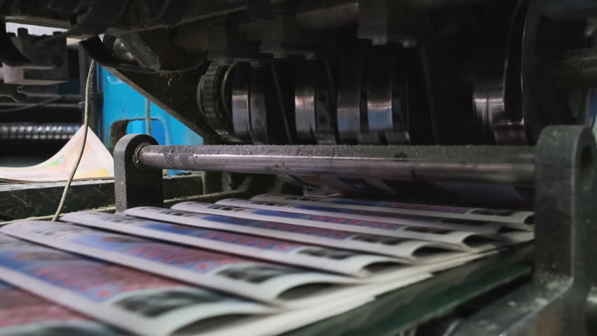 Industrial printing press operating in a printing house, efficiently producing and sorting newspapers for distribution. The machinery showcases modern printing technology in action.