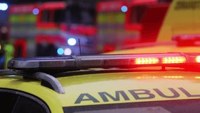 Close-up of blue and red light flasher on roof of ambulance car of emergency medical service on road against fire engines. Themes rescue, accidents and disasters. - Powered by Shutterstock - Get 15% off with code: PIKWIZARD15