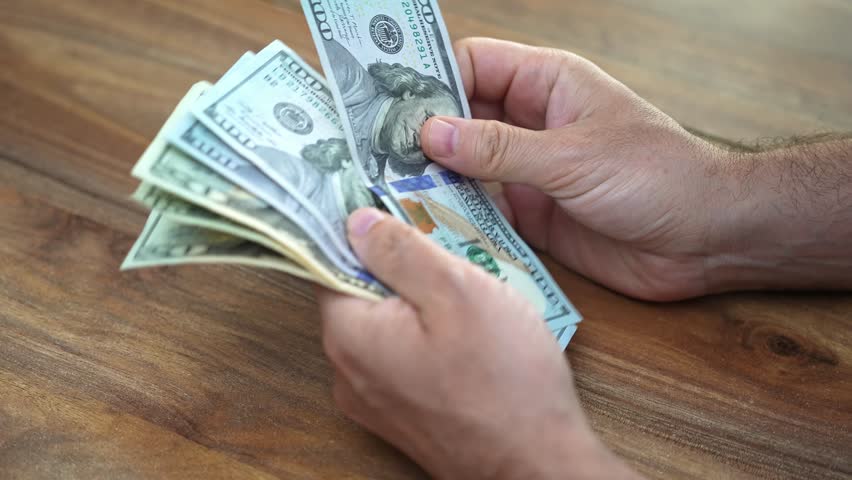 Male financial planner counts dollar bills to organize clients emergency cash fund providing peace of mind in case of unexpected financial needs during month