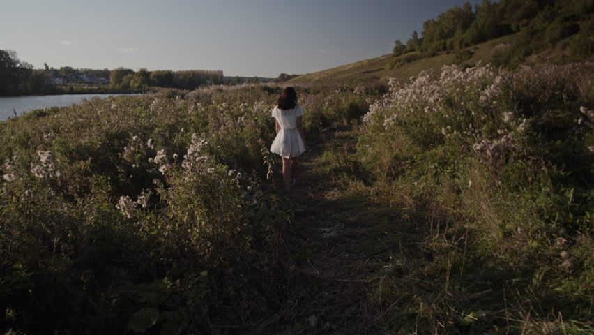 Anonymous woman walking near river in countryside