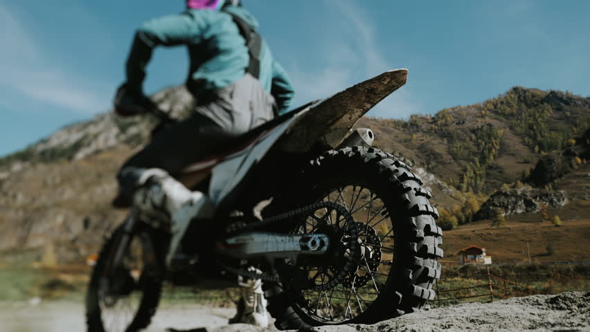 Motocross racer starts moving on sand, close-up of bike wheel. Sand flies from under a motorcycle wheel. A sharp start of a motorcycle in the sand.
