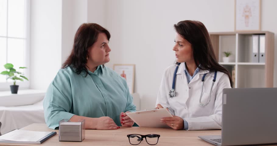 Doctor gives consultation to fat large chubby overweight obese woman, answers questions, explains, prescribes diet, shares advice on wellness, lifestyle, nutrition, weight loss and body mass control