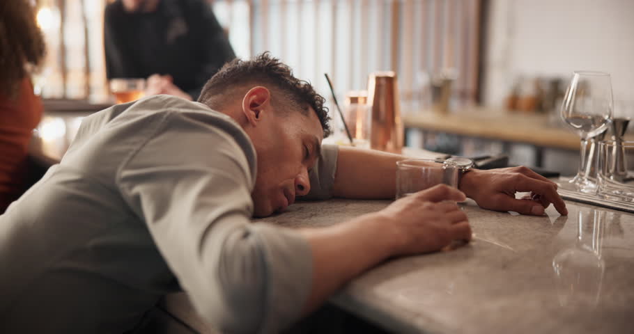 Man, sleeping and alcohol drink at pub for depression, tired drunk and addiction problem of whiskey abuse. Male person, fatigue and nap with liquor beer, stress management and grief mistake for debt