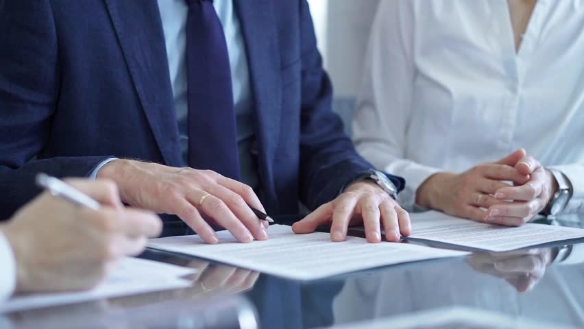 Business people wearing suits signing important documents during a corporate meeting. Win-win concept