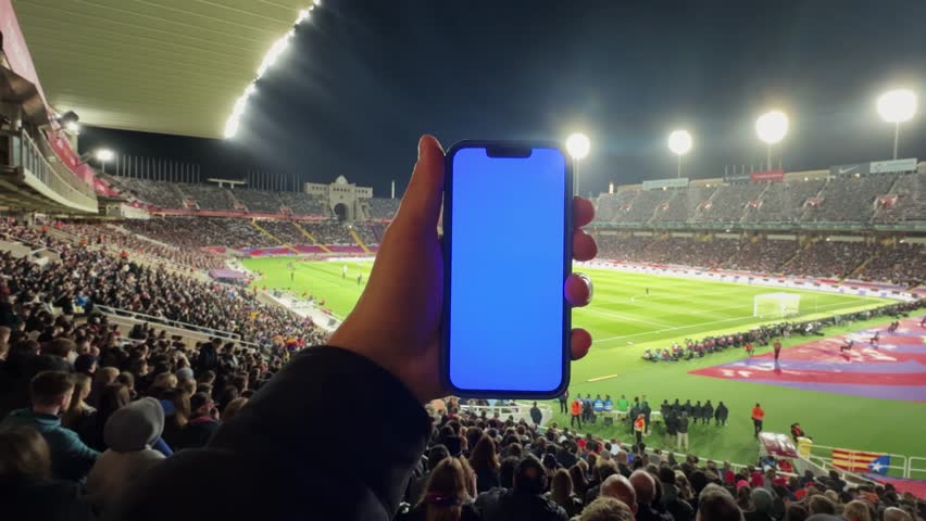 International soccer football championship on stadium: Fan on tribune holding smartphone with Chroma Key Display, Cheering for favourite team. - Powered by Shutterstock - Get 15% off with code: PIKWIZARD15