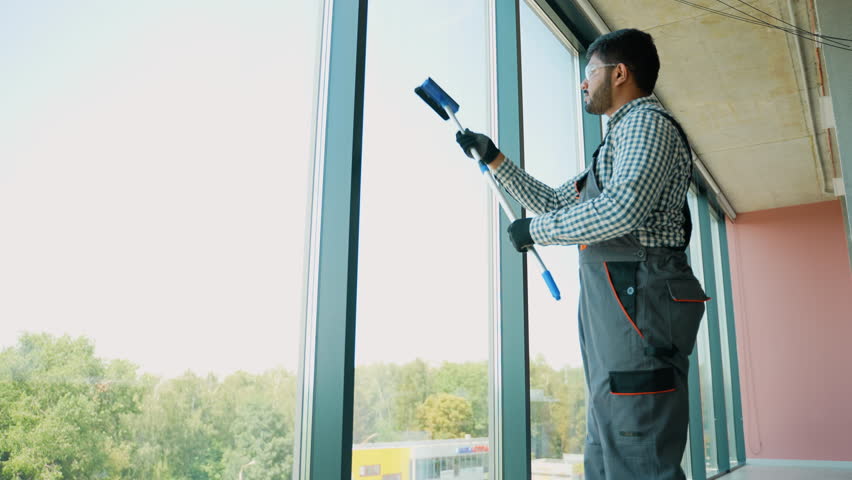 Pakistani service worker cleaning office windows, cleaning service