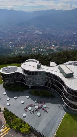 4K DRONE AERIAL VIEW : Employees of a company rally in favor of breast cancer placed in the shape of a ribbon all dressed in pink, with the building and the city in background, in Medellin Colombia