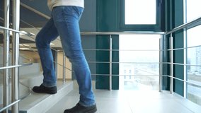 An adult man climbs the stairs of an office building. A businessman in blue jeans in a joint building. - Powered by Shutterstock - Get 15% off with code: PIKWIZARD15