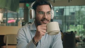 Indian ethnic guy male businessman freelancer visitor cafe drink coffee break smiling business man listen music headphones drinking tea in restaurant airport happy client earphones enjoy audio relax - Powered by Shutterstock - Get 15% off with code: PIKWIZARD15