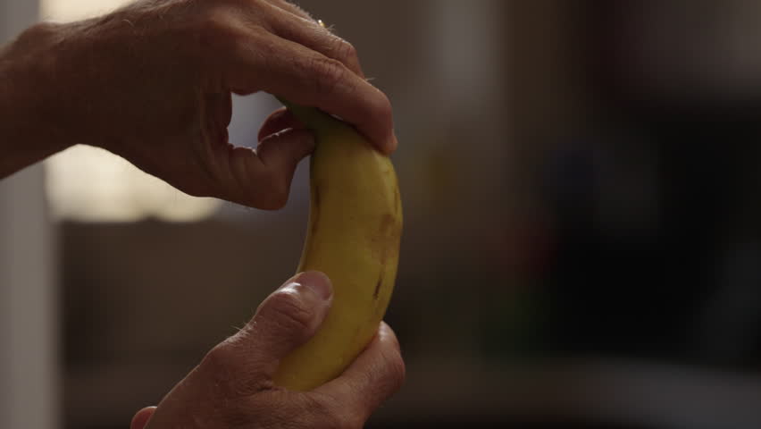 close-up man's hands peeling a banana