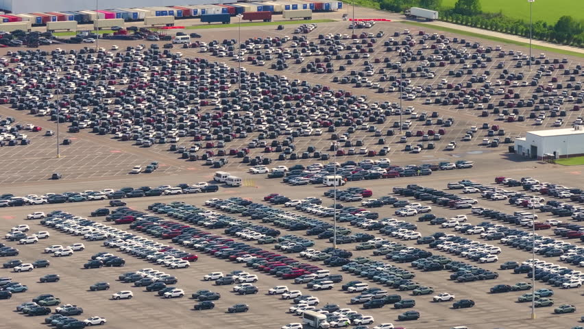 Parked new cars at the automotive plant factory parking lot ready for sale. Development of American industry concept.