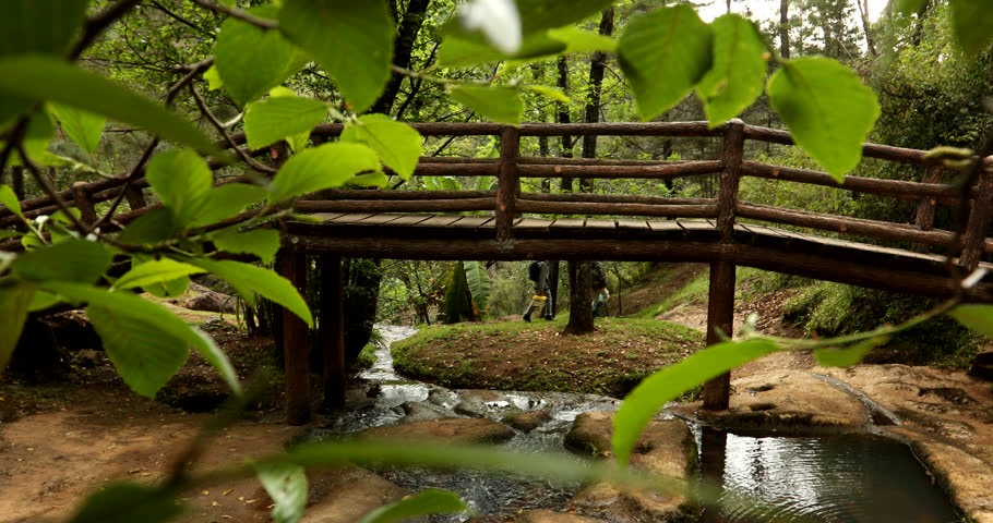 Cloudy afternoon view of a stream running under a wooden bridge in a public park in Mazamitla, Jalisco, Mexico.