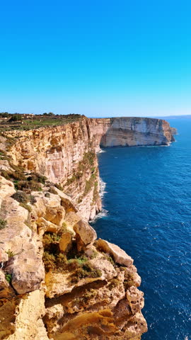 Footage at the edge of the cliff on the coastline of Ireland. Beautiful rocky shore on sunny daytime. Vertical video.